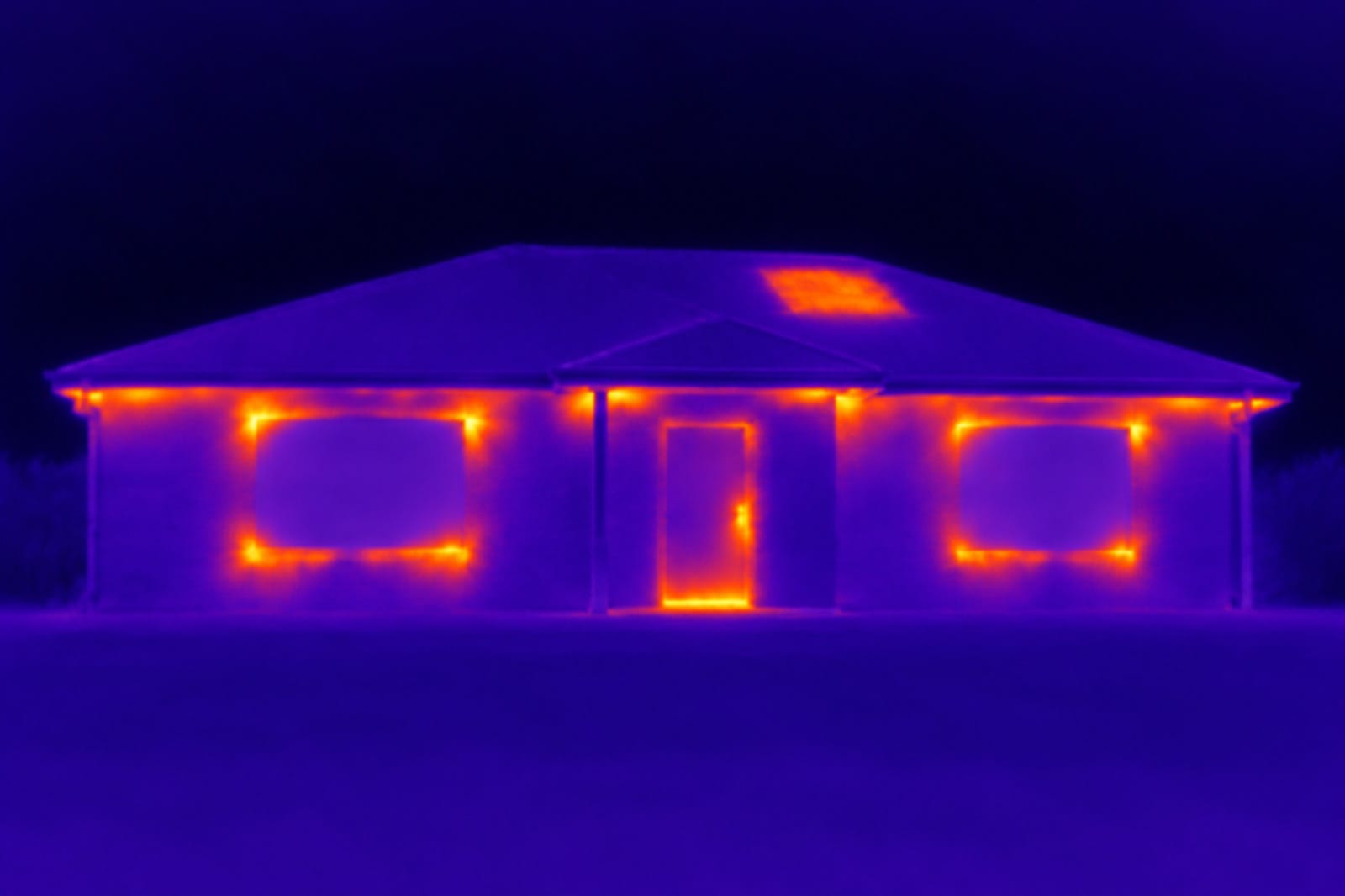 A single-storey brick veneer house seen through a thermal camera at night: heat escapes around the windows, the front door and under the eaves